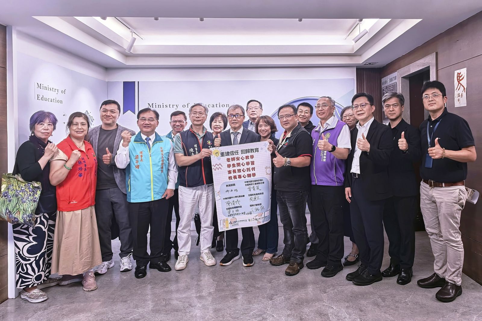教師、校長與家長團體代表在教育部合影，手持「重建信任　回歸教育」簽名看板